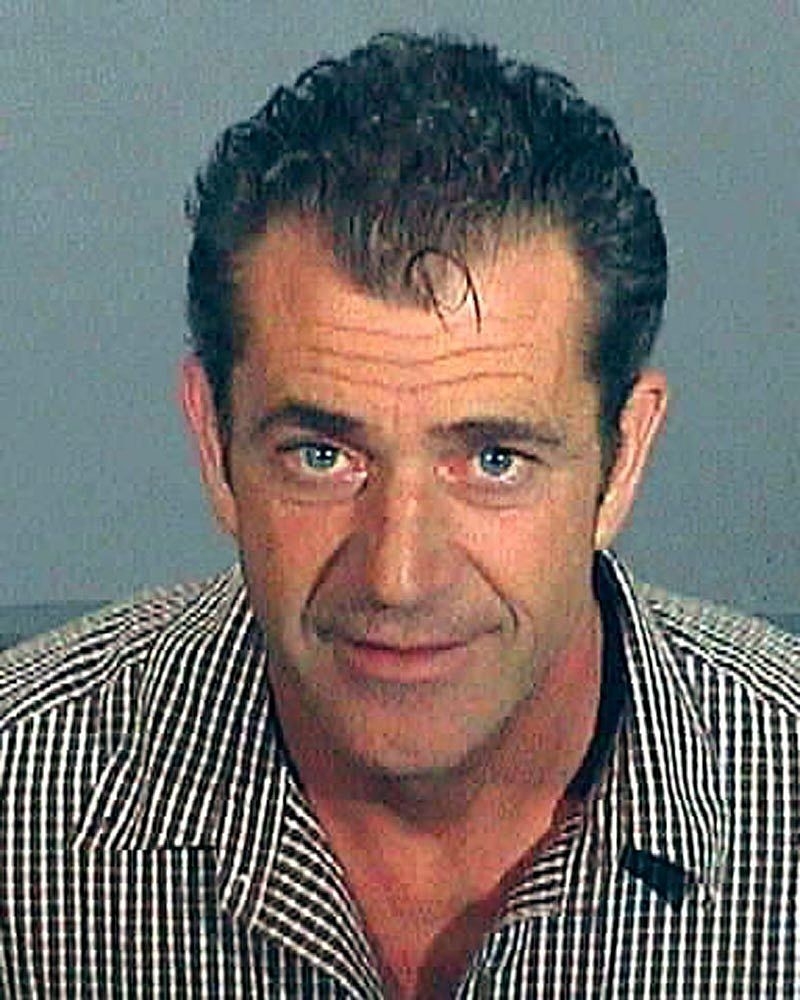 A man with slicked-back hair and a striped shirt, looking at the camera
