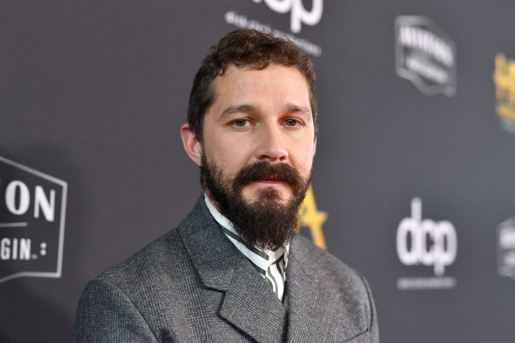 Shia LaBeouf on the red carpet wearing a formal gray suit at a celebrity event