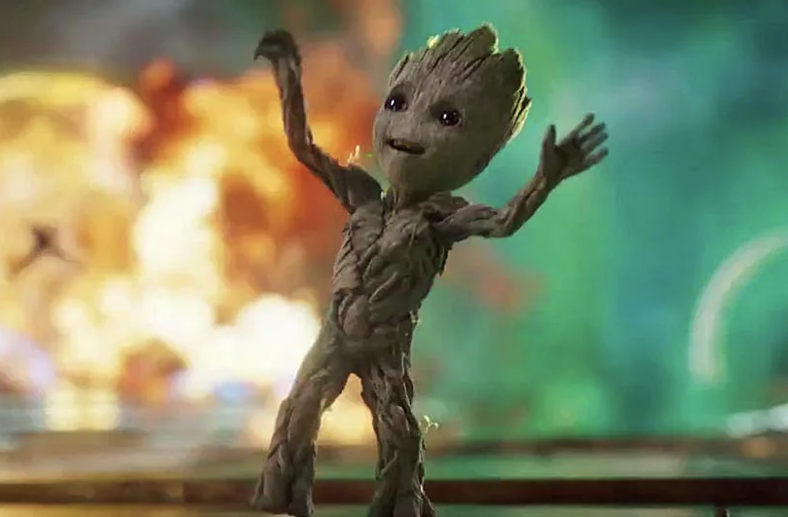 Baby Groot from Guardians of the Galaxy stands with arms raised in a celebratory pose, with a blurred, dynamic background