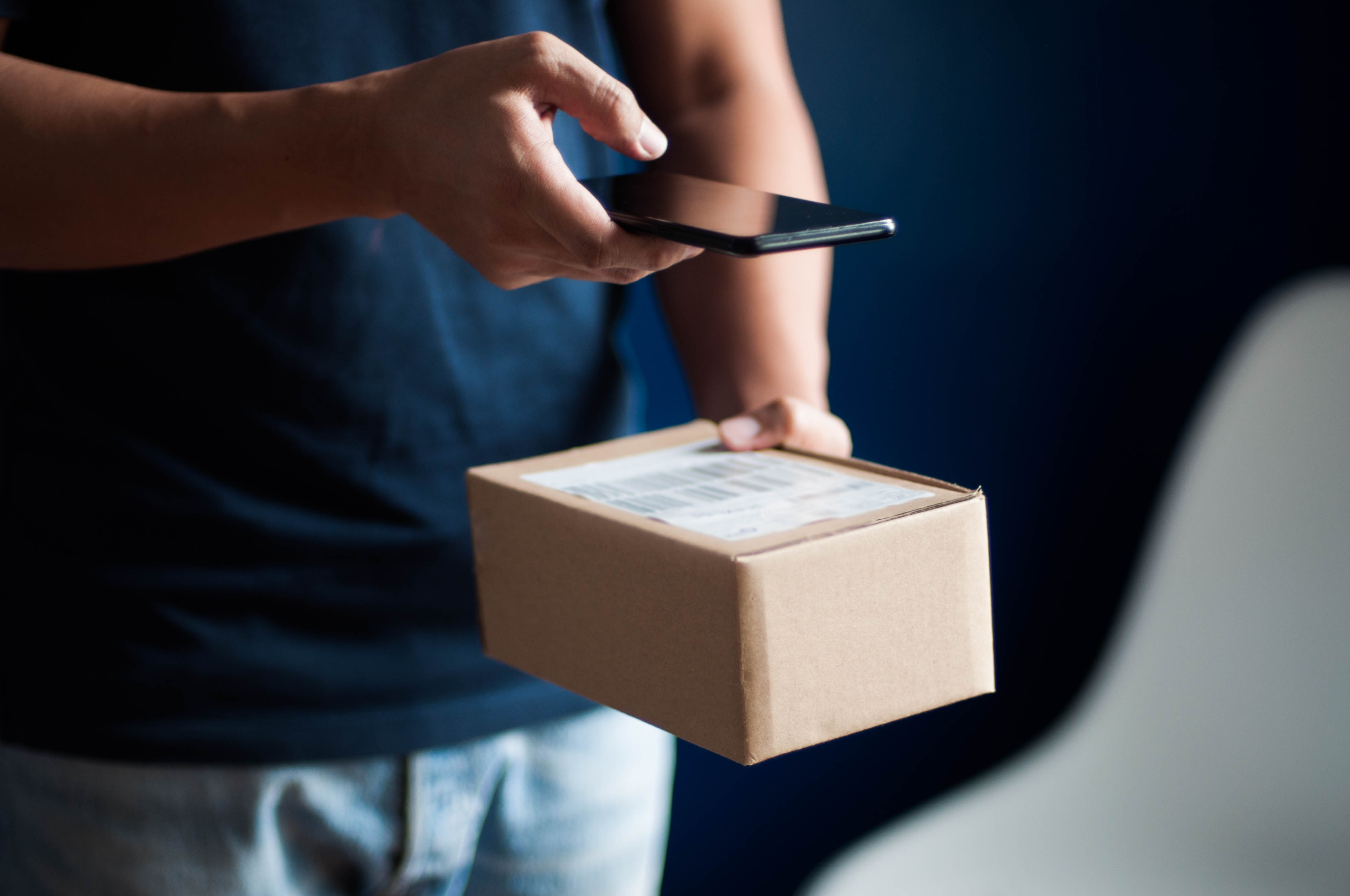 Person holding a smartphone and scanning a package with a barcode