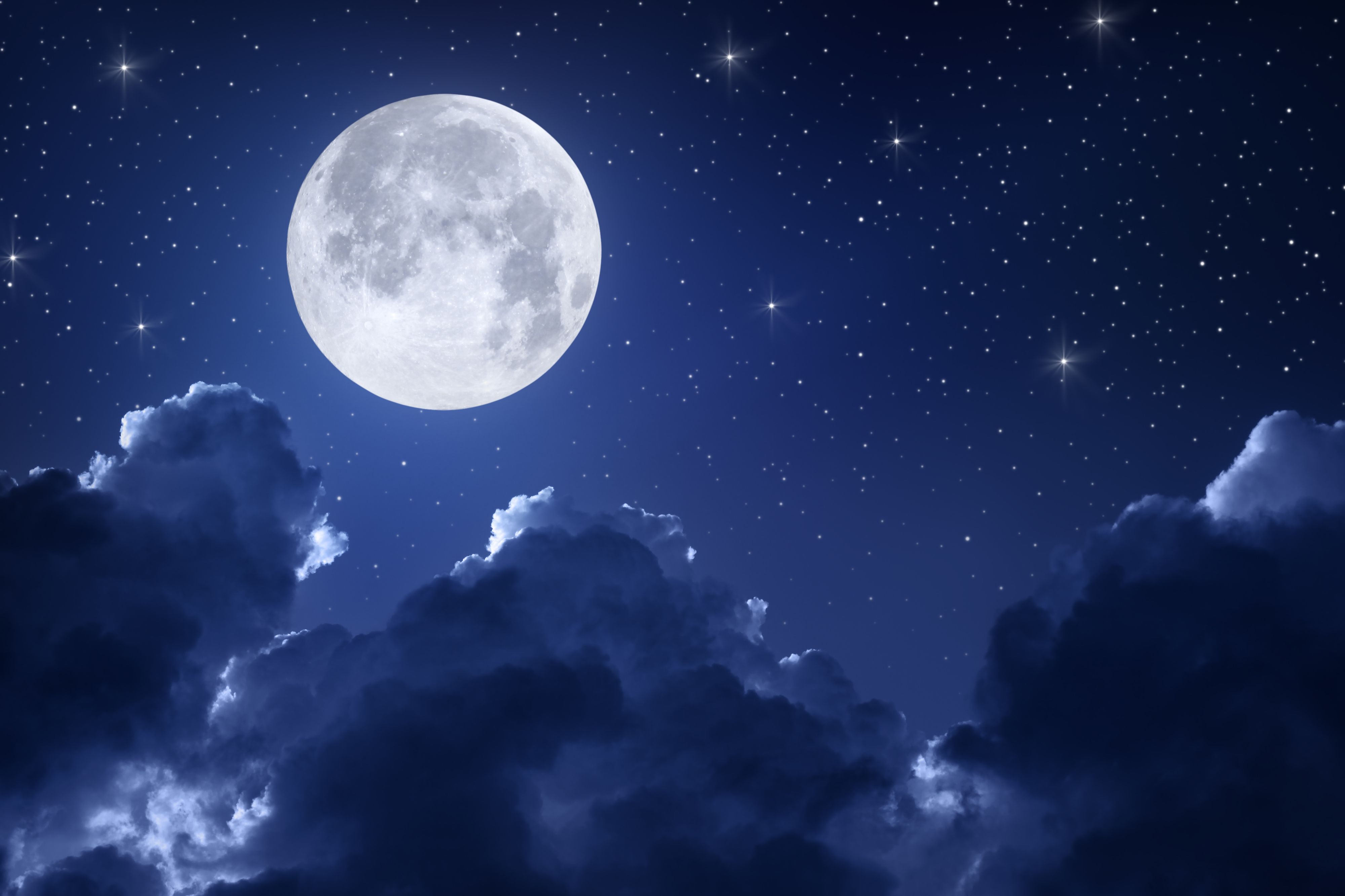 Full moon shining brightly in a star-filled night sky, with clouds scattered below