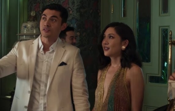 Henry Golding in a white suit and Constance Wu in a stylish gown in a scene from a movie