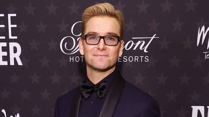 Man in dark suit and bow tie with glasses at a red-carpet event