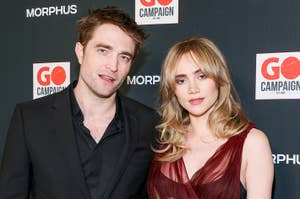 Robert Pattinson and Suki Waterhouse pose together in elegant evening wear at the GO Campaign event backdrop