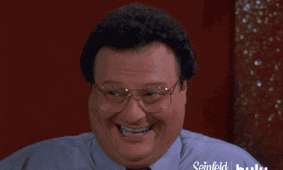 Wayne Knight as Newman from Seinfeld smiles and laughs during a scene