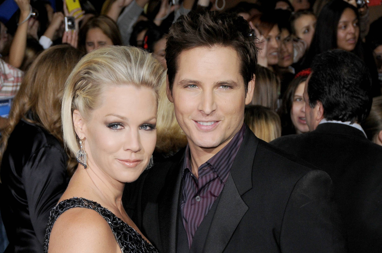 Jennie Garth and Peter Facinelli pose together on the red carpet, both wearing elegant attire, with a crowd in the background
