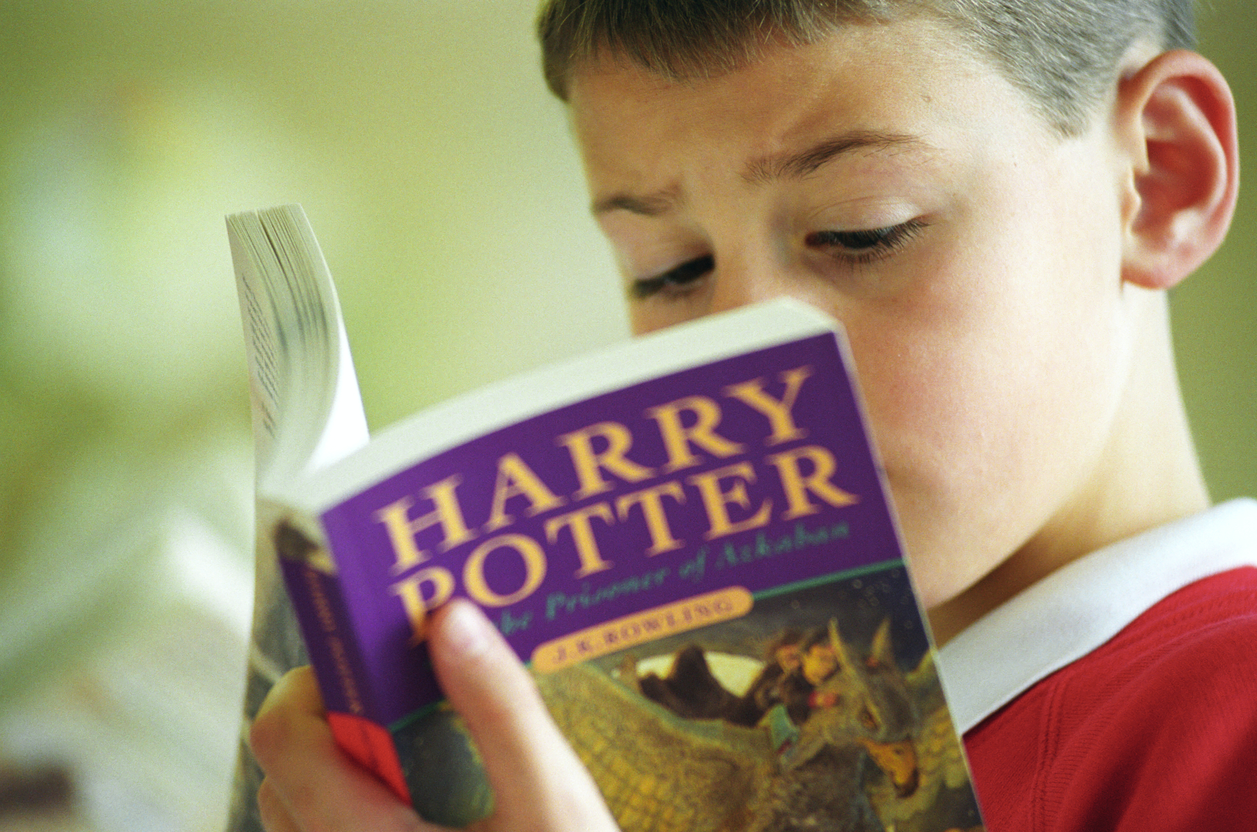 A young boy reads "Harry Potter and the Prisoner of Azkaban" by J.K. Rowling