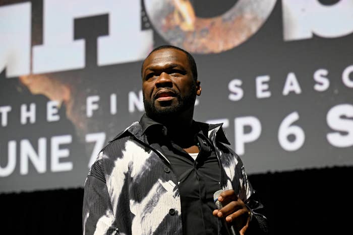 50 Cent on stage wearing a patterned jacket, holding a microphone, in front of a screen displaying promotional text for &quot;Power: The Final Season.&quot;