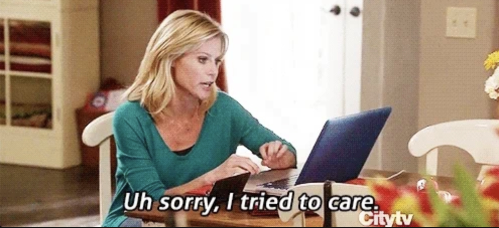 Julie Bowen's character, Claire Dunphy, sits at a table looking at a laptop, with text below saying, "Uh sorry, I tried to care." Scene from a TV show