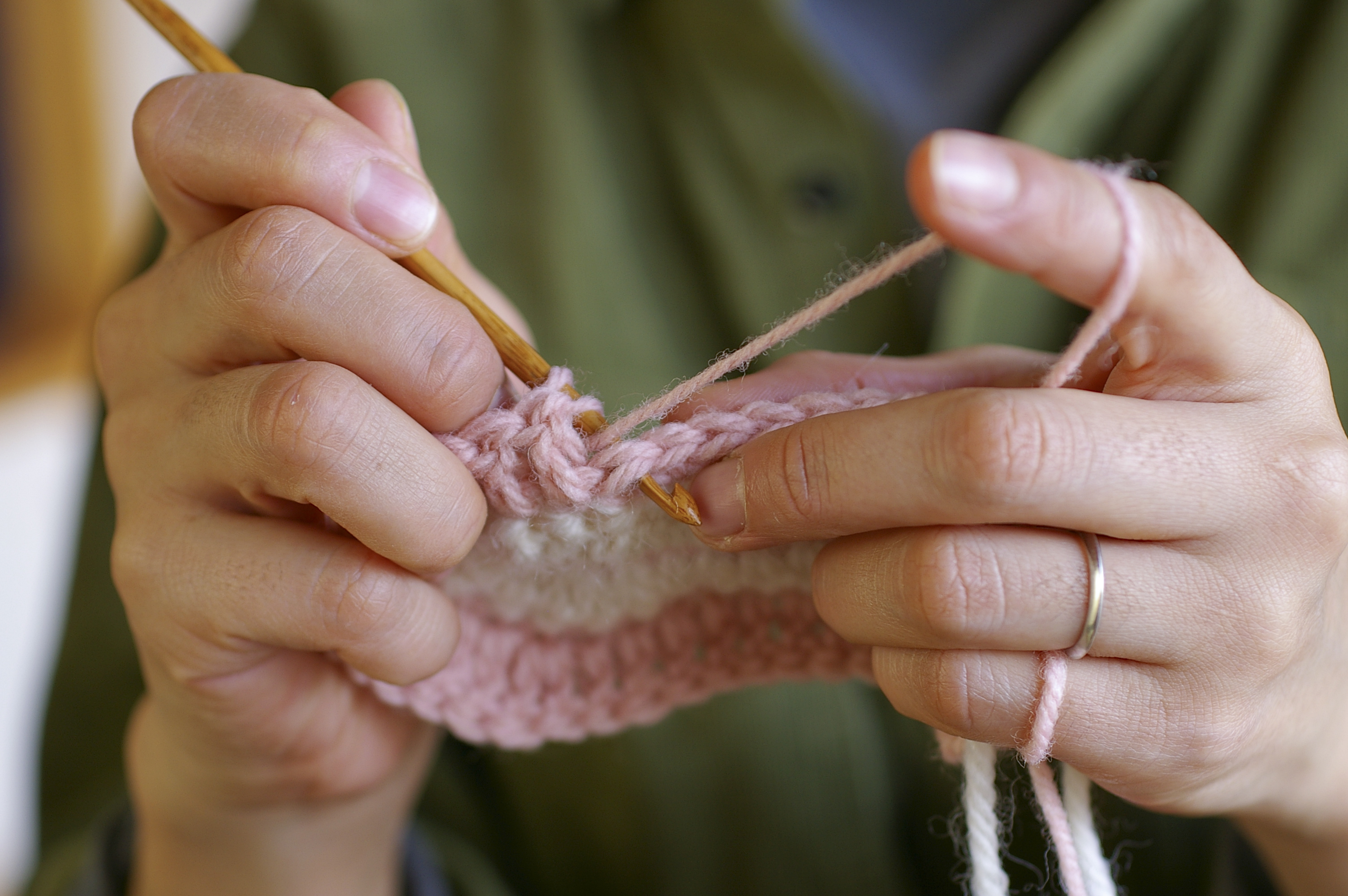 Close-up of hands holding a crochet needle, working on a piece of yarn