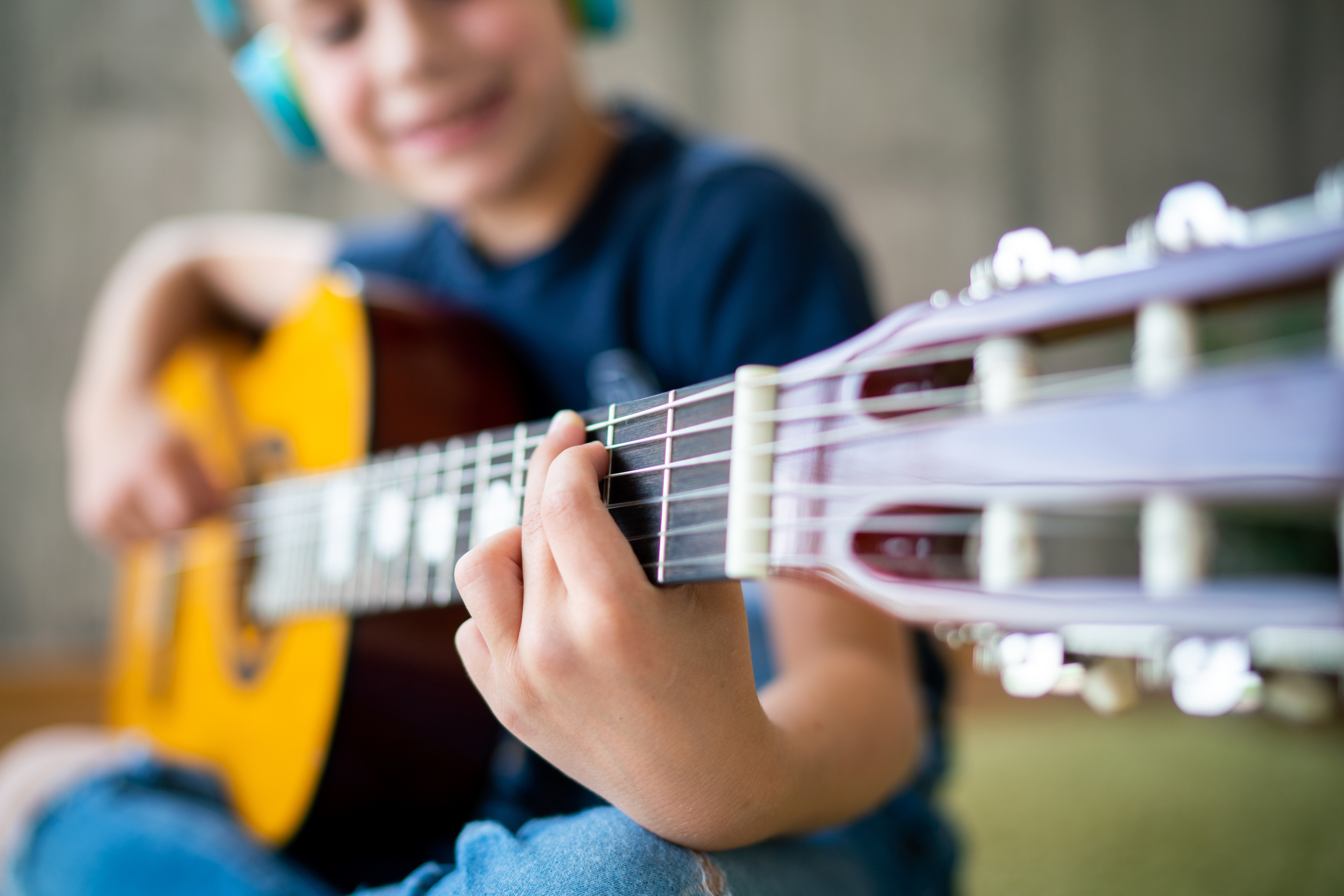 Child wearing headphones playing an acoustic guitar