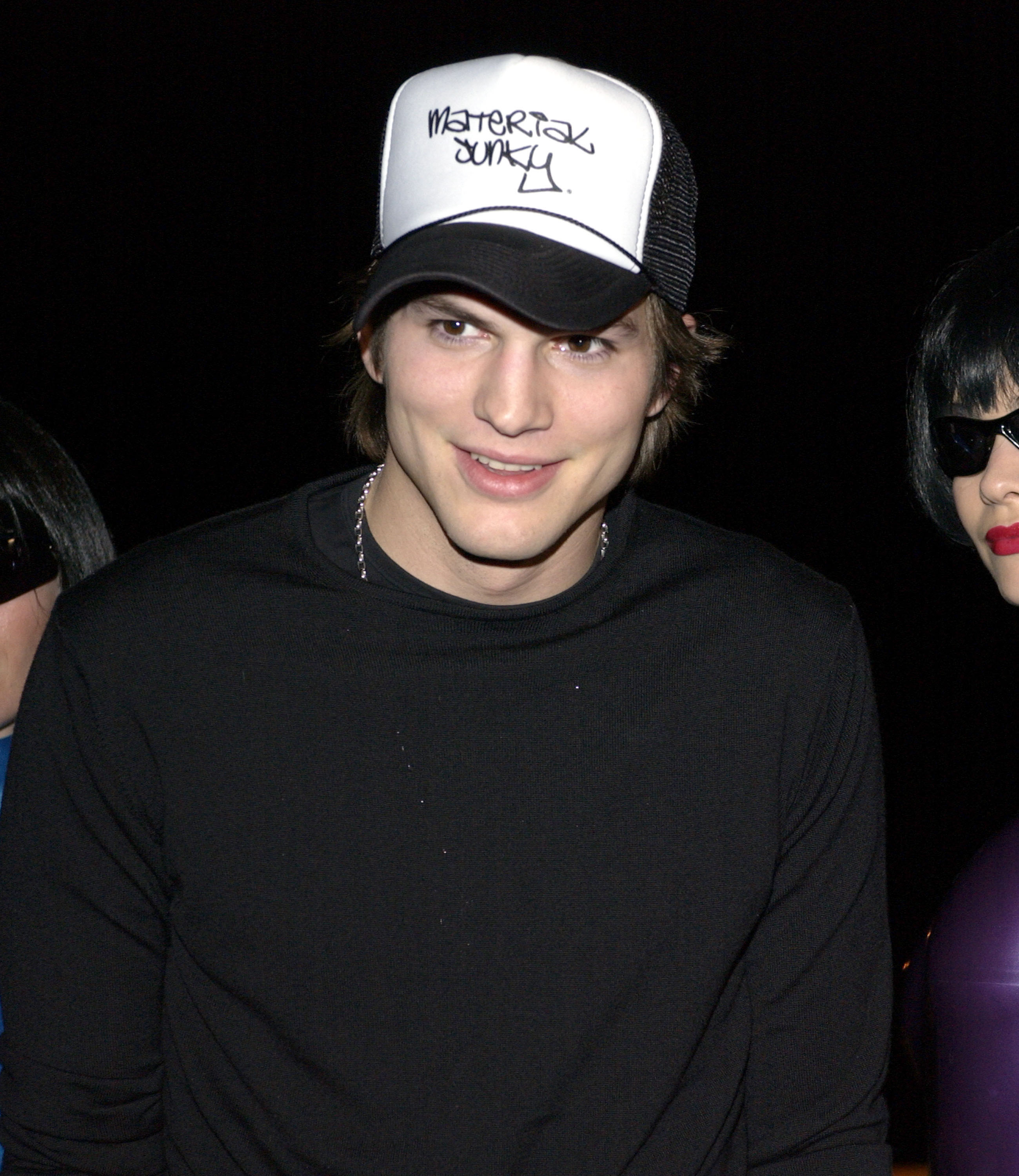 Ashton Kutcher wearing a trucker style baseball cap with "Material Junky" written on it