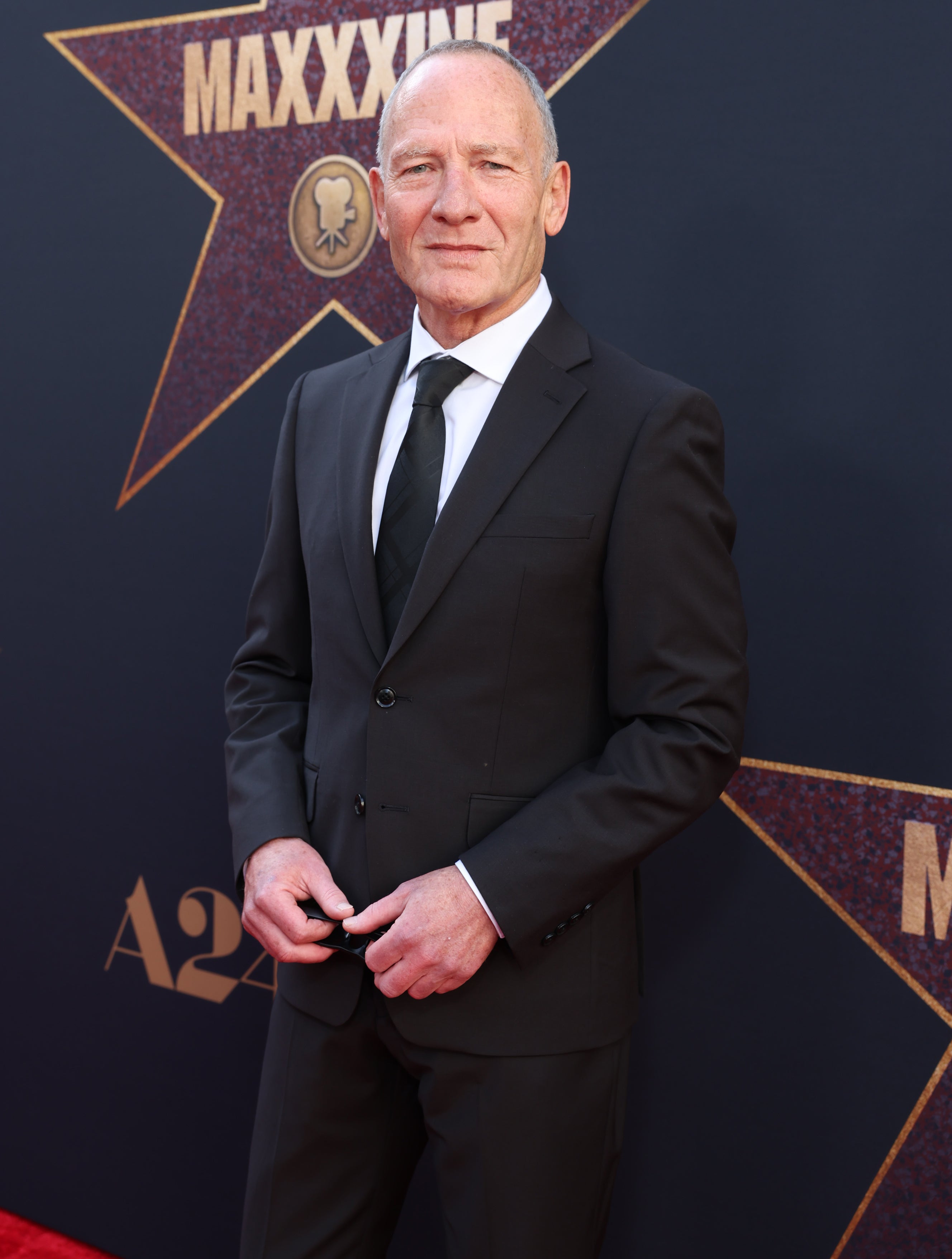 Simon Prast in a suit and tie at the premiere of "MaXXXine"