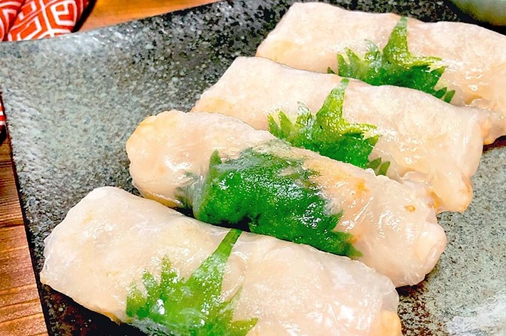 皿に盛られた、青シソで飾られた生春巻き4本。手前に醤油が入った小皿も見える。