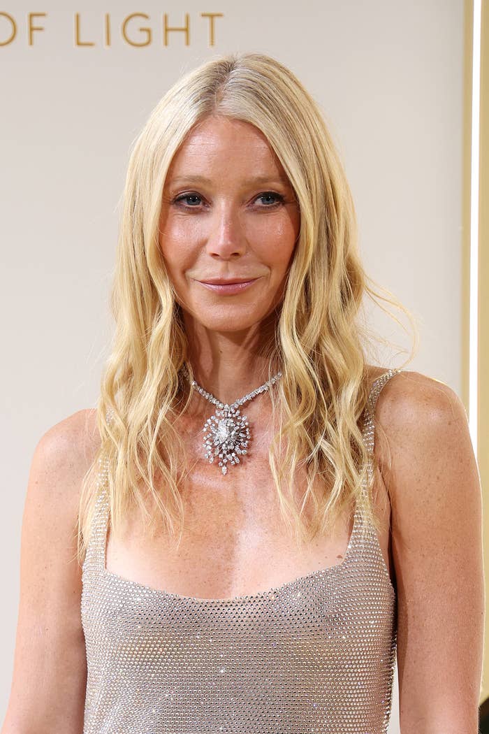 Gwyneth Paltrow on a red carpet, wearing a sparkly, sleeveless dress with a statement necklace
