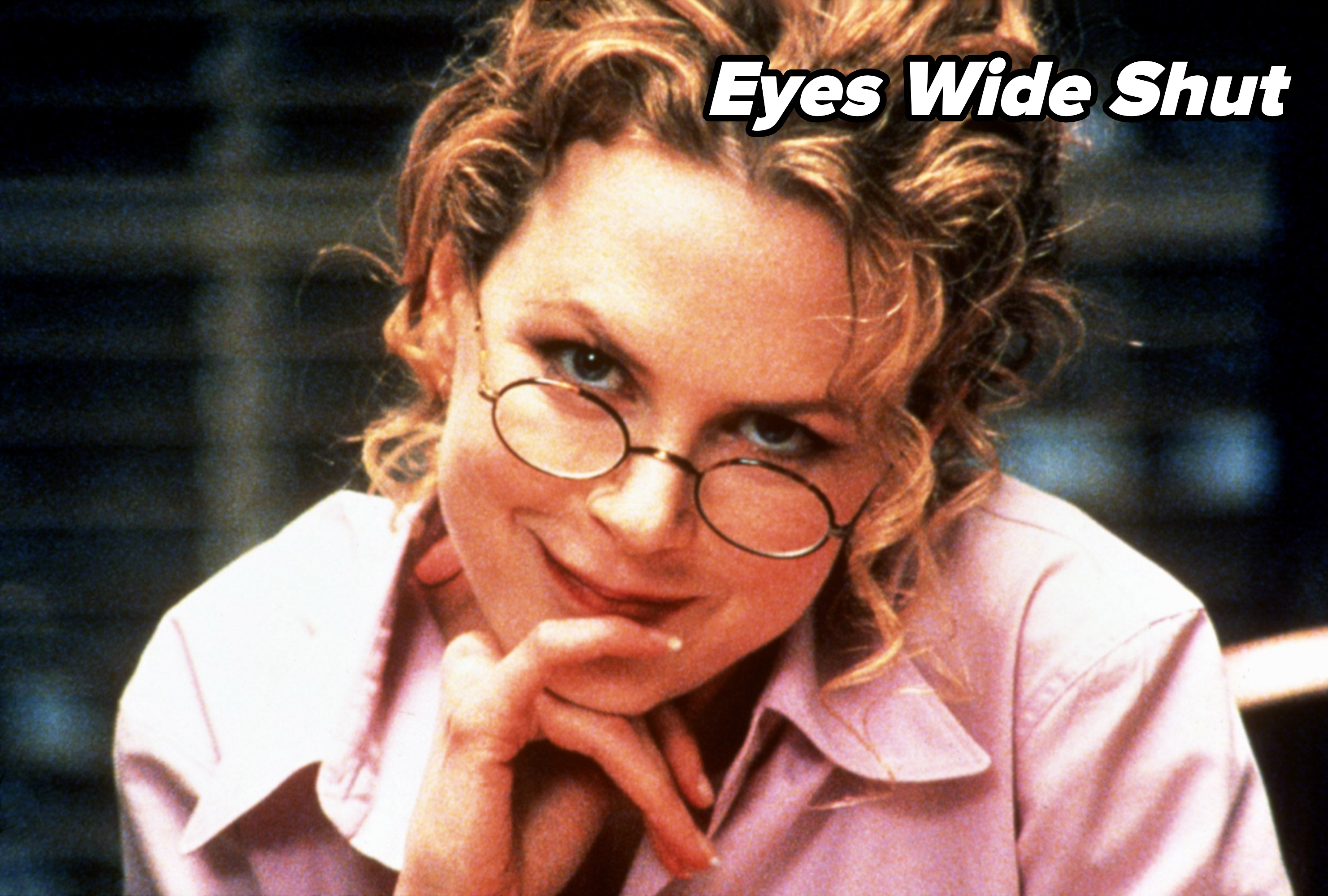 Nicole Kidman wears glasses and a shirt, smiling with her chin resting on her hand in a close-up shot