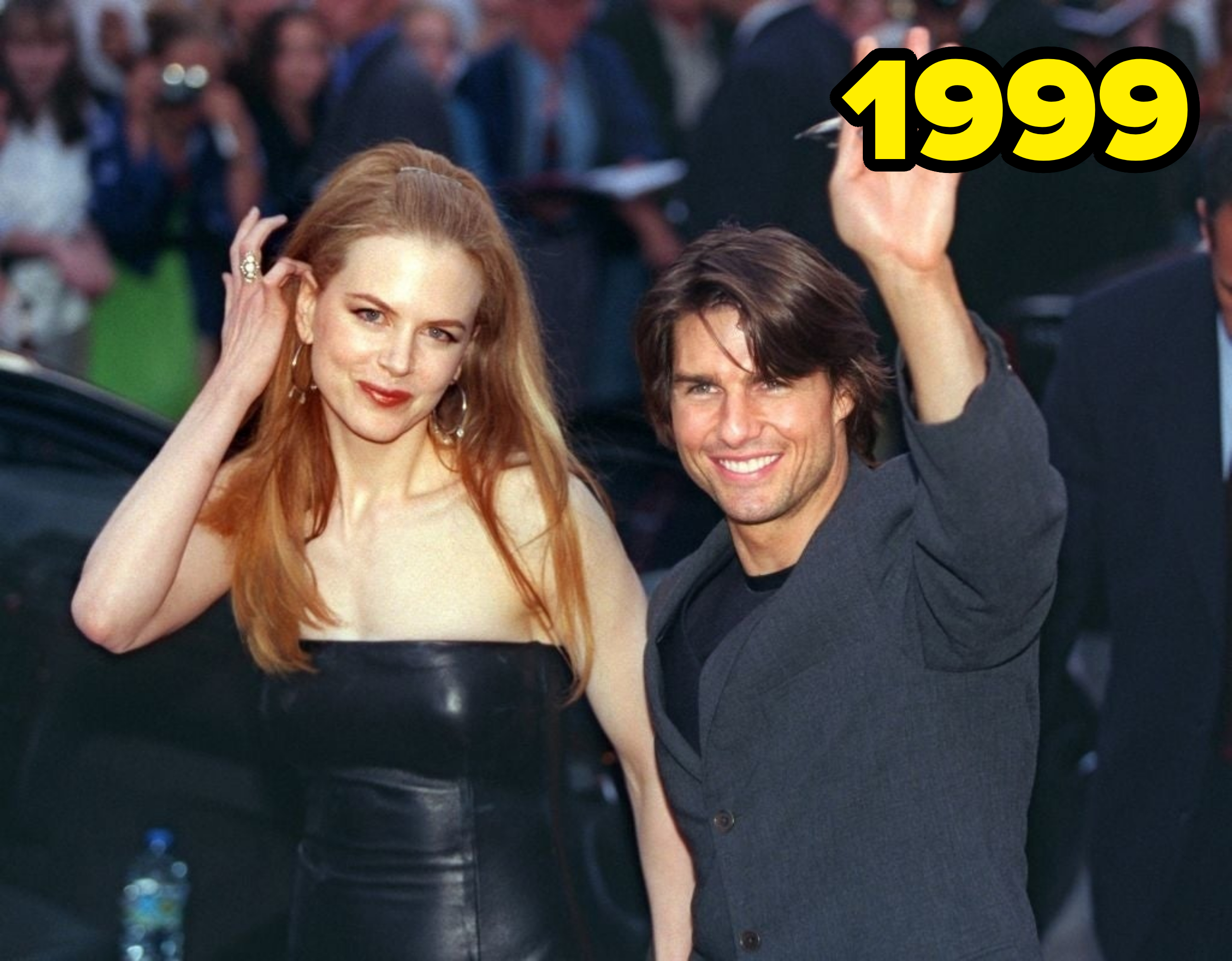 Nicole Kidman in a strapless leather dress and Tom Cruise in a suit wave and smile at a public event