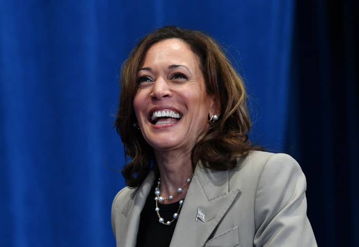 Kamala Harris smiling broadly in a professional setting, wearing a blazer and pearl necklace