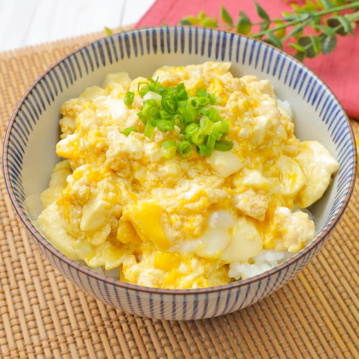 ご飯にのせたふわふわの卵丼がボウルに盛られています。刻んだネギがトッピングされています。