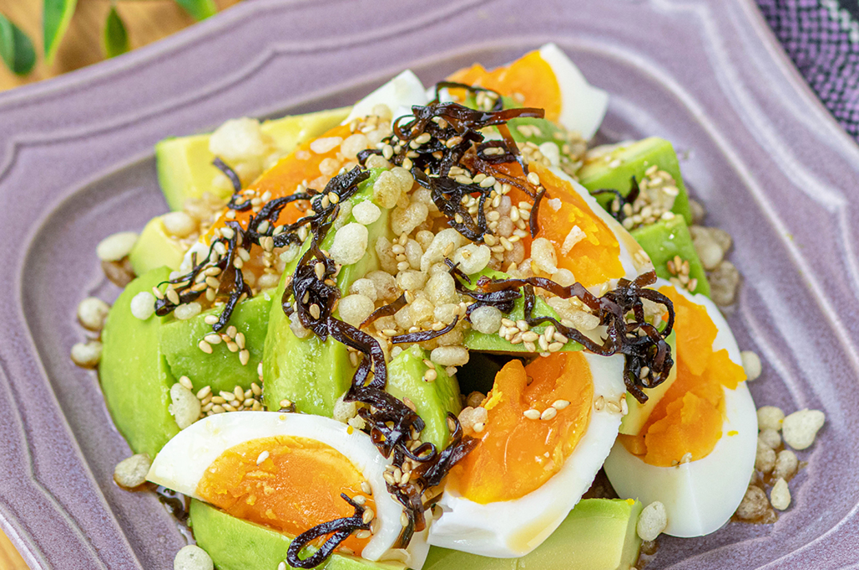 アボカド、ゆで卵、ゴマ、玄米ポンせんべいが入ったサラダが皿に盛り付けられています。