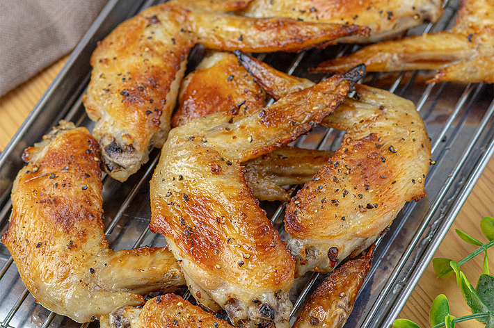 金属トレーに並べられた数枚のローストチキンウィング。おいしそうに焼き上げられている。