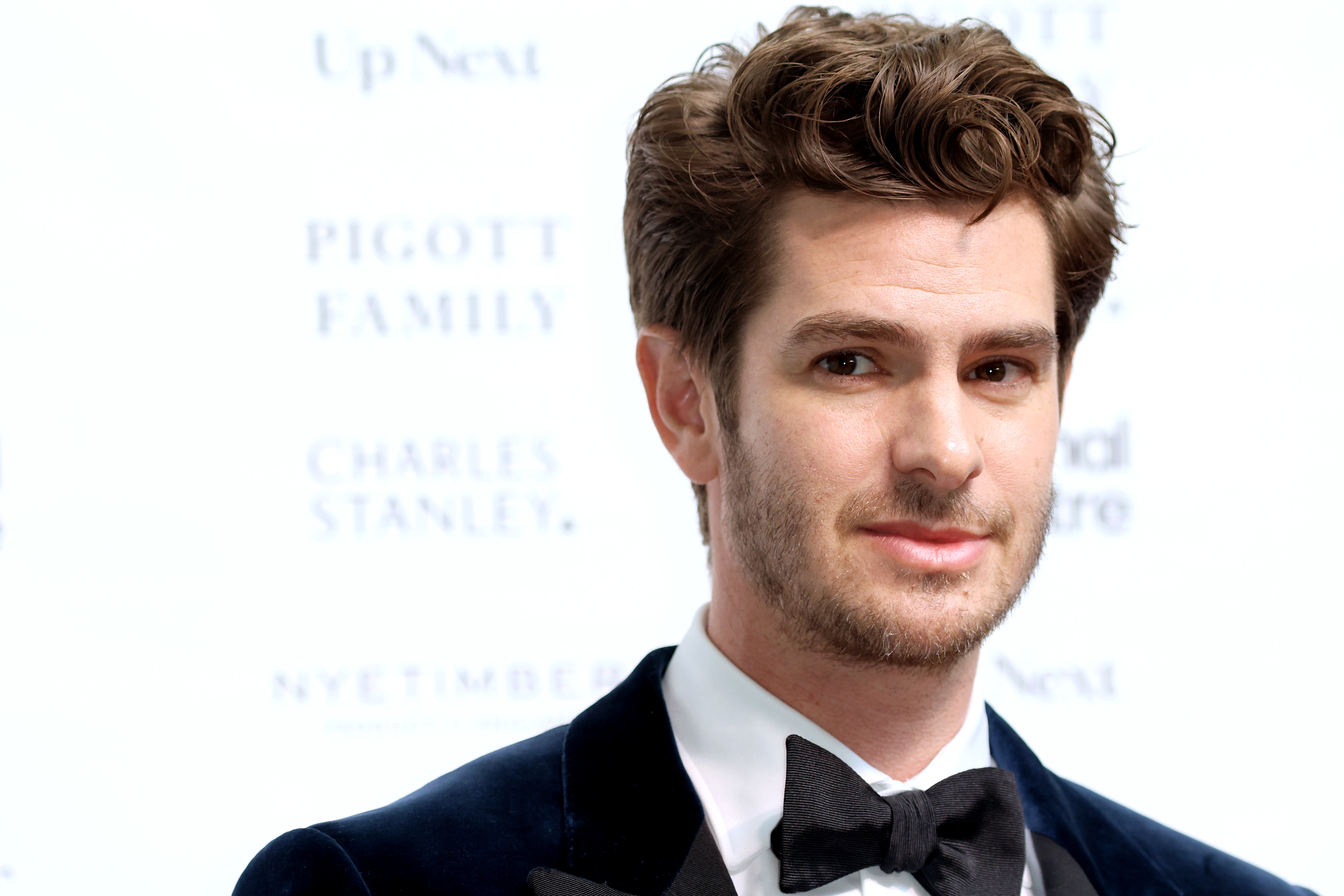 Andrew Garfield in a formal suit with a bow tie at a press event