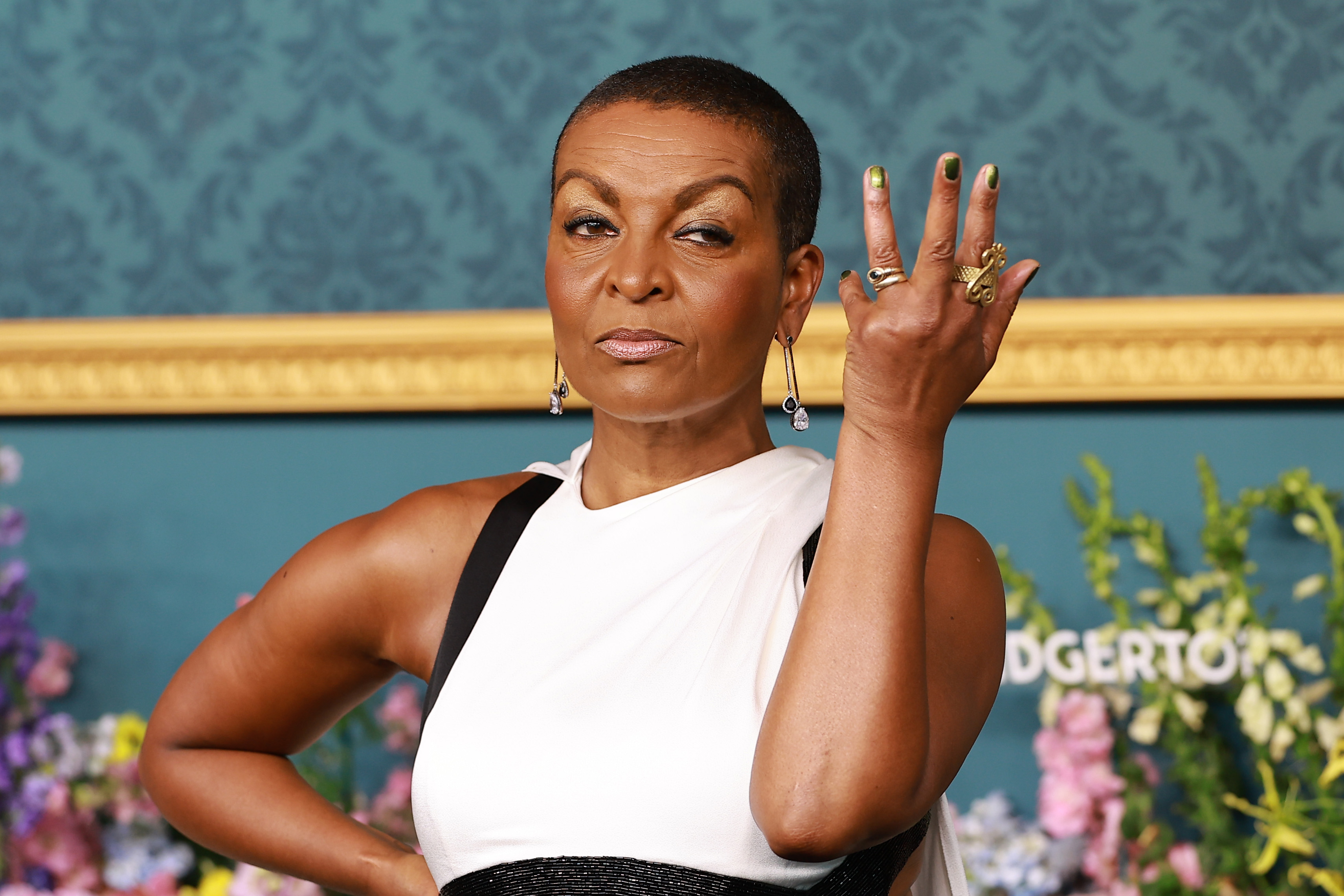 Adjoa Andoh strikes a confident pose in an elegant, sleeveless outfit with statement jewelry at a press event for "Bridgerton"