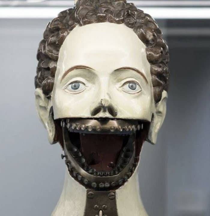 A mannequin head with an open mechanical mouth, resembling a dental training tool