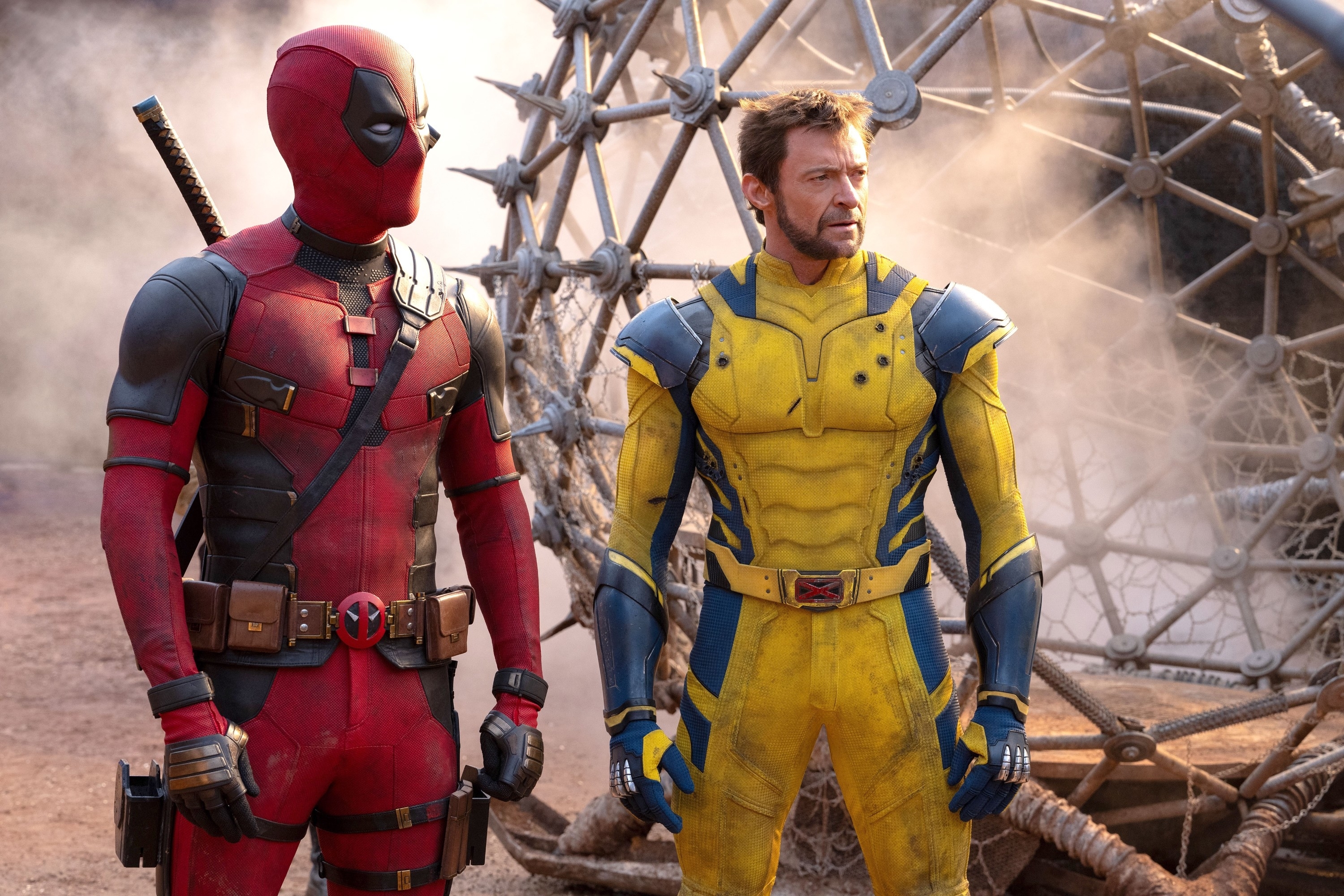 Deadpool (Ryan Reynolds) and Wolverine (Hugh Jackman) standing side by side in superhero costumes on a movie set