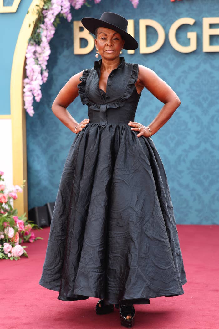 Adjoa Andoh wears a sleeveless, ruffled gown and a wide-brimmed hat on the red carpet