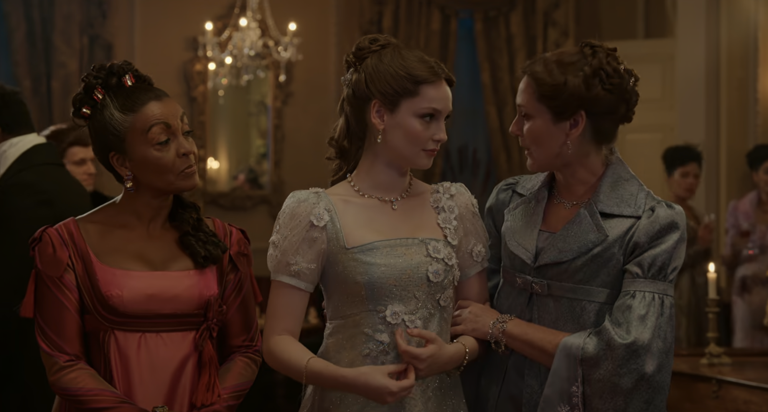 Adjoa Andoh, Claudia Jessie, and Ruth Gemmell in elegant period dresses at a formal gathering from the TV show "Bridgerton"