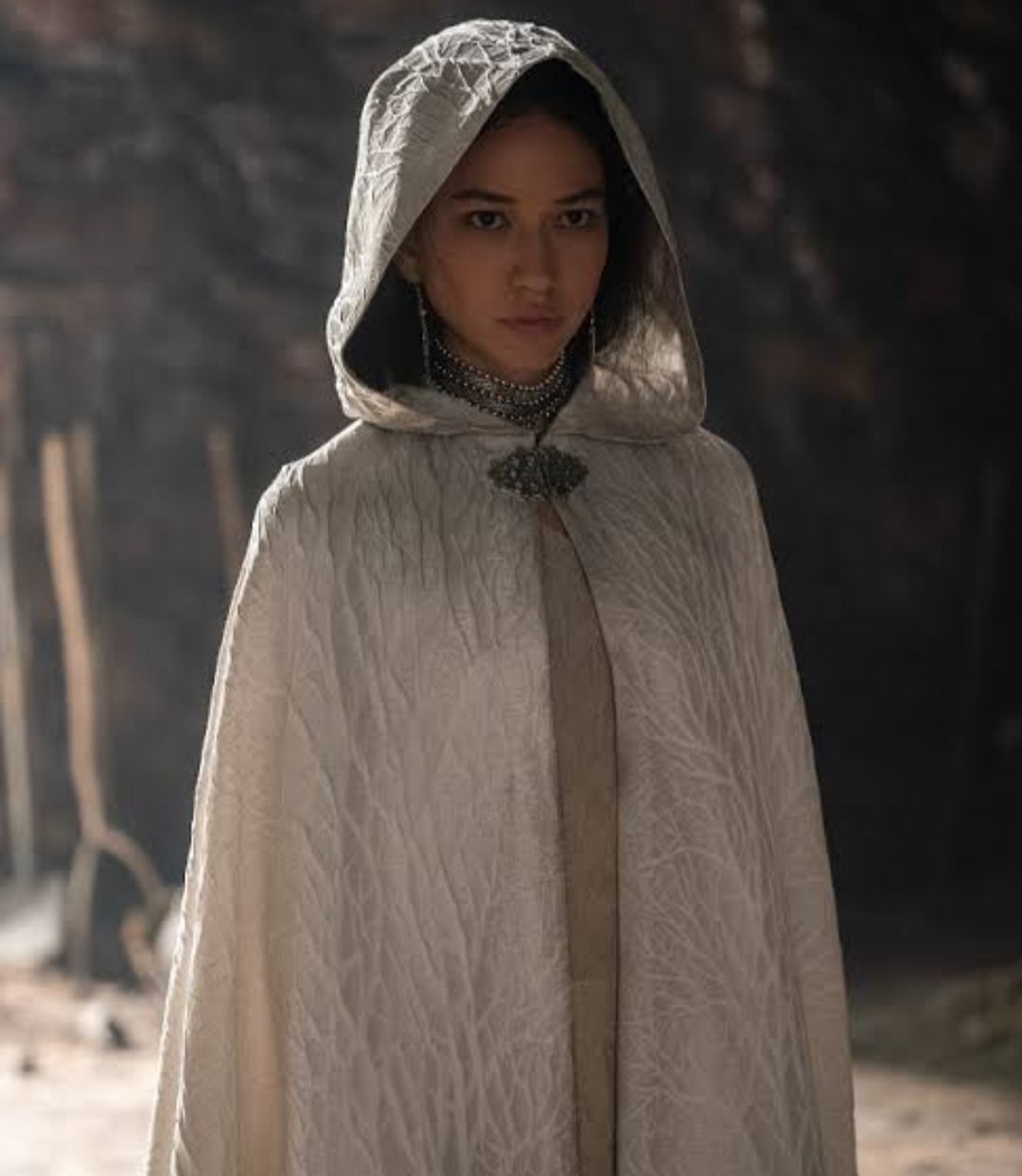 Amber Midthunder, con capa de estilo medieval con capucha, en una escena de TV