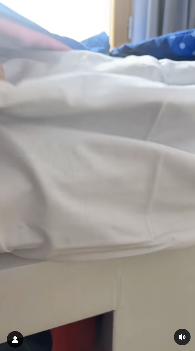 Unidentified person appears to be resting on a bed with a white sheet