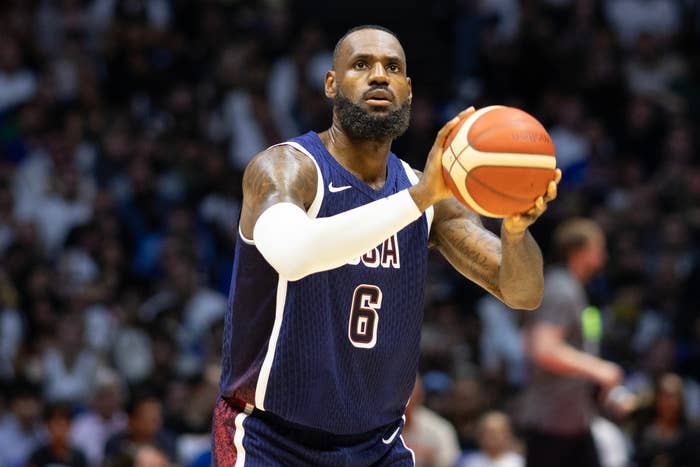 LeBron James is preparing to shoot a basketball during a game, wearing a sleeveless jersey with "USA" and the number 6