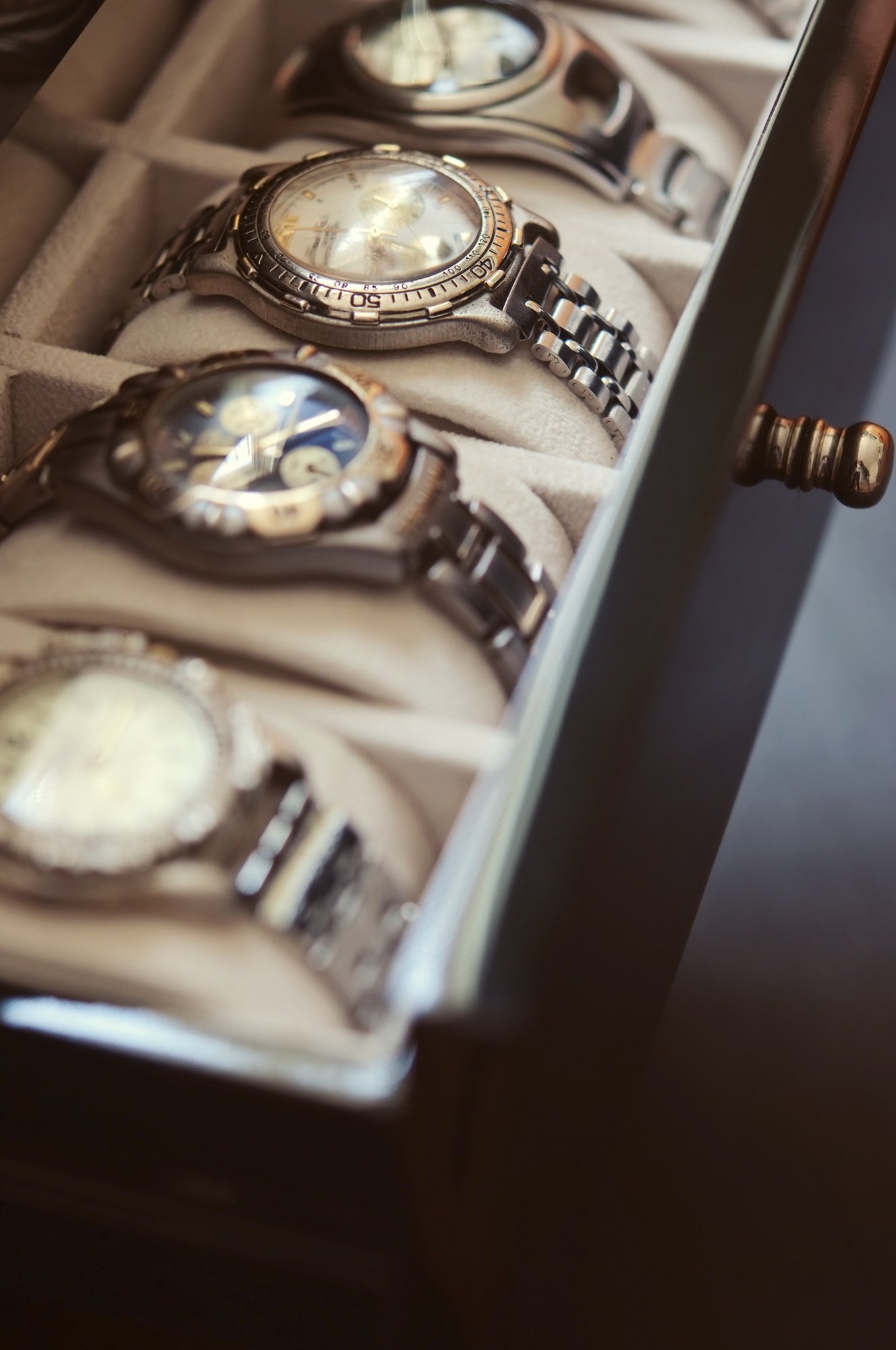 A collection of luxury wristwatches displayed in a drawer with padded compartments
