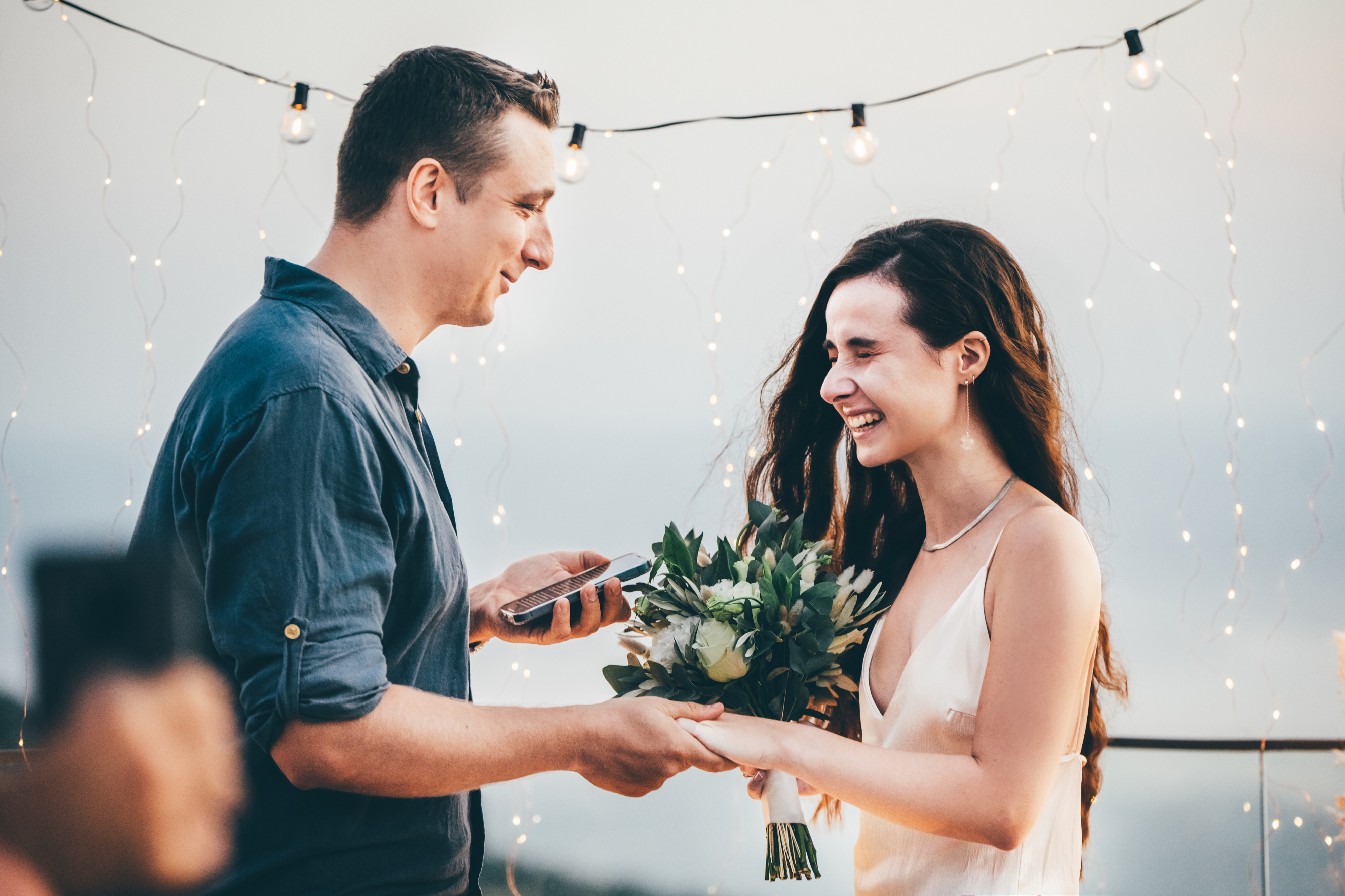 A man and woman reading marriage vows surrounded by twinkly lights