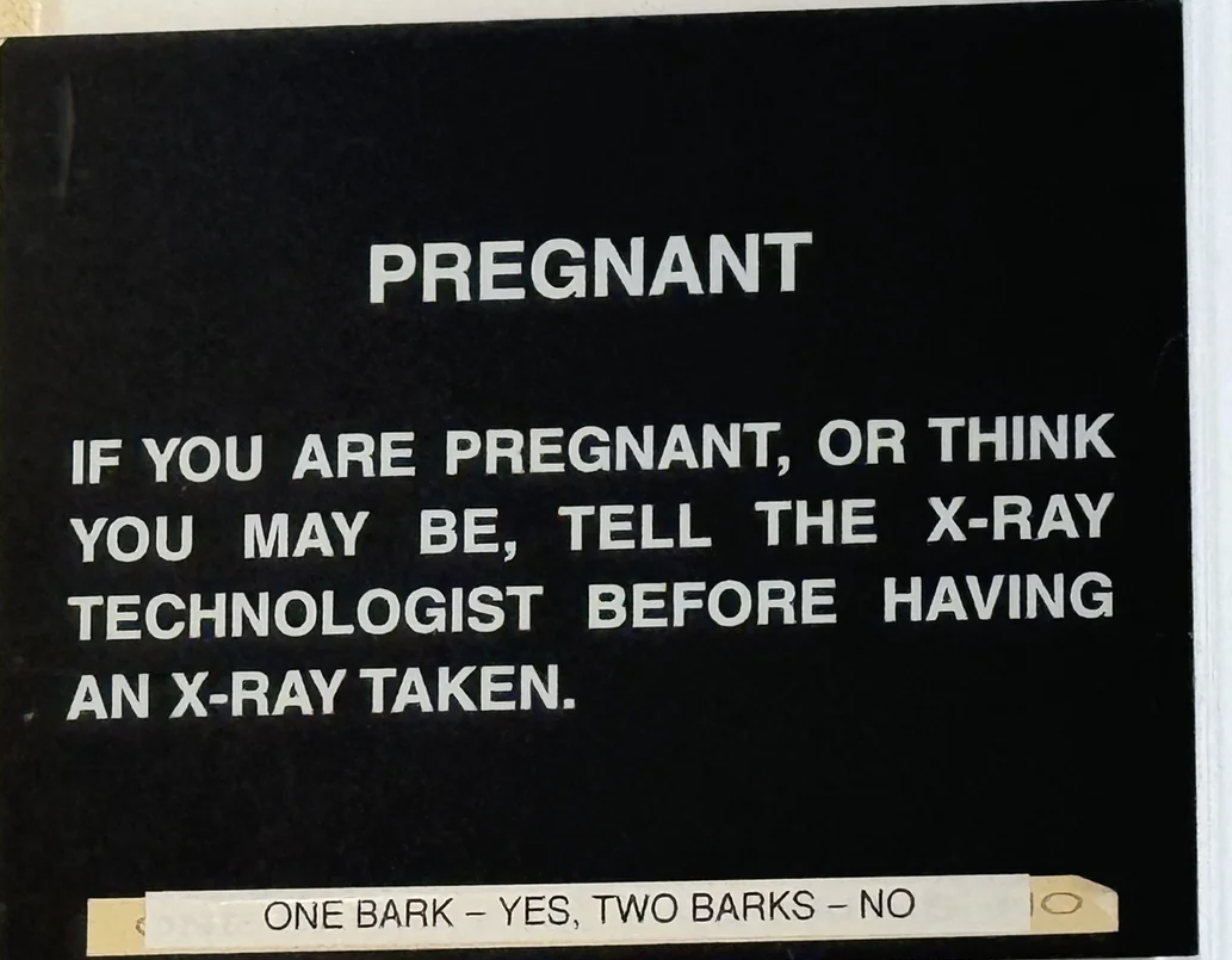 Sign reads: "Pregnant. If you are pregnant, or think you may be, tell the X-ray technologist before having an X-ray taken." Below text: "One bark - yes, two barks - no."