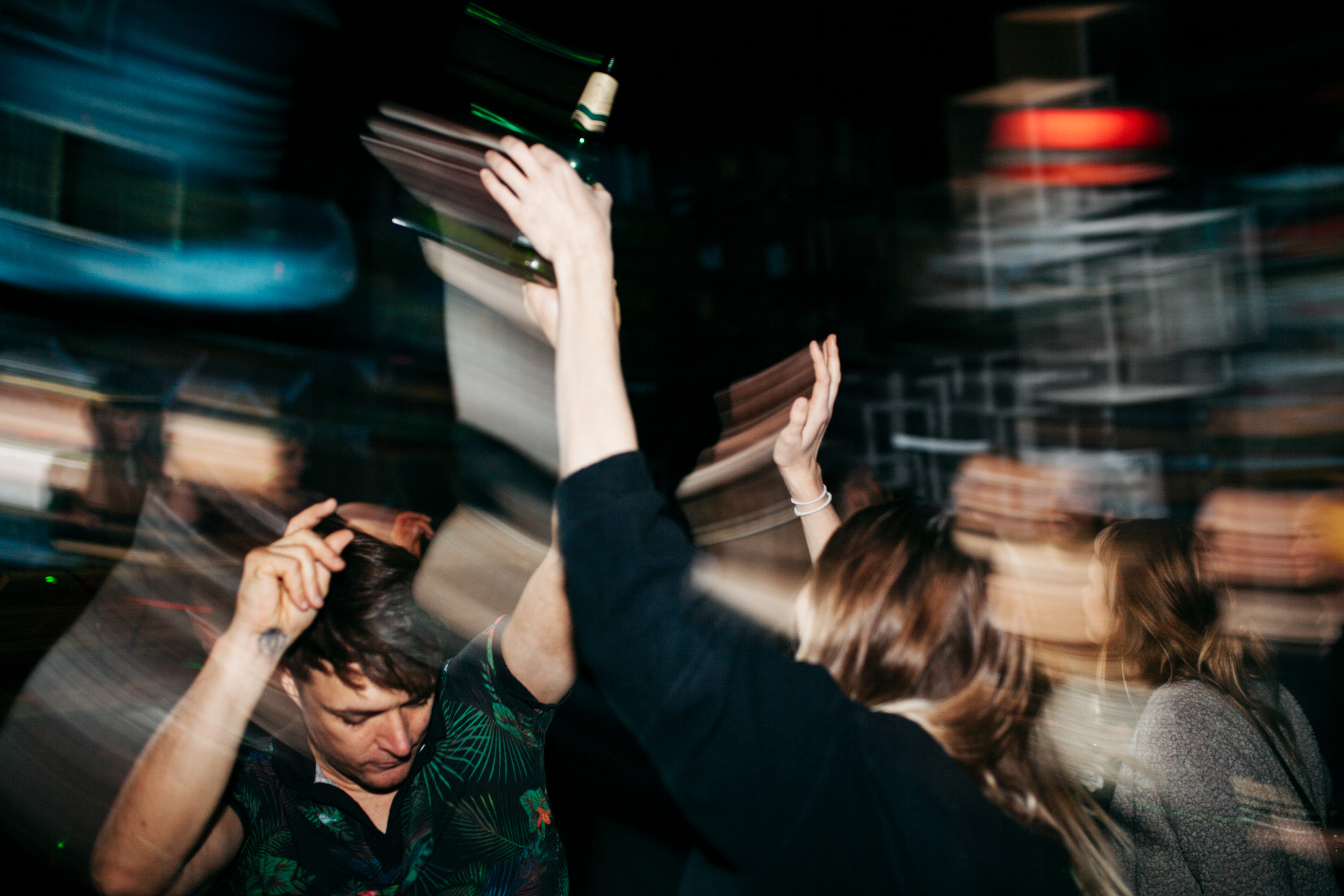 People dancing energetically at a party, their movements captured in a blur. Faces and identities are not clearly visible