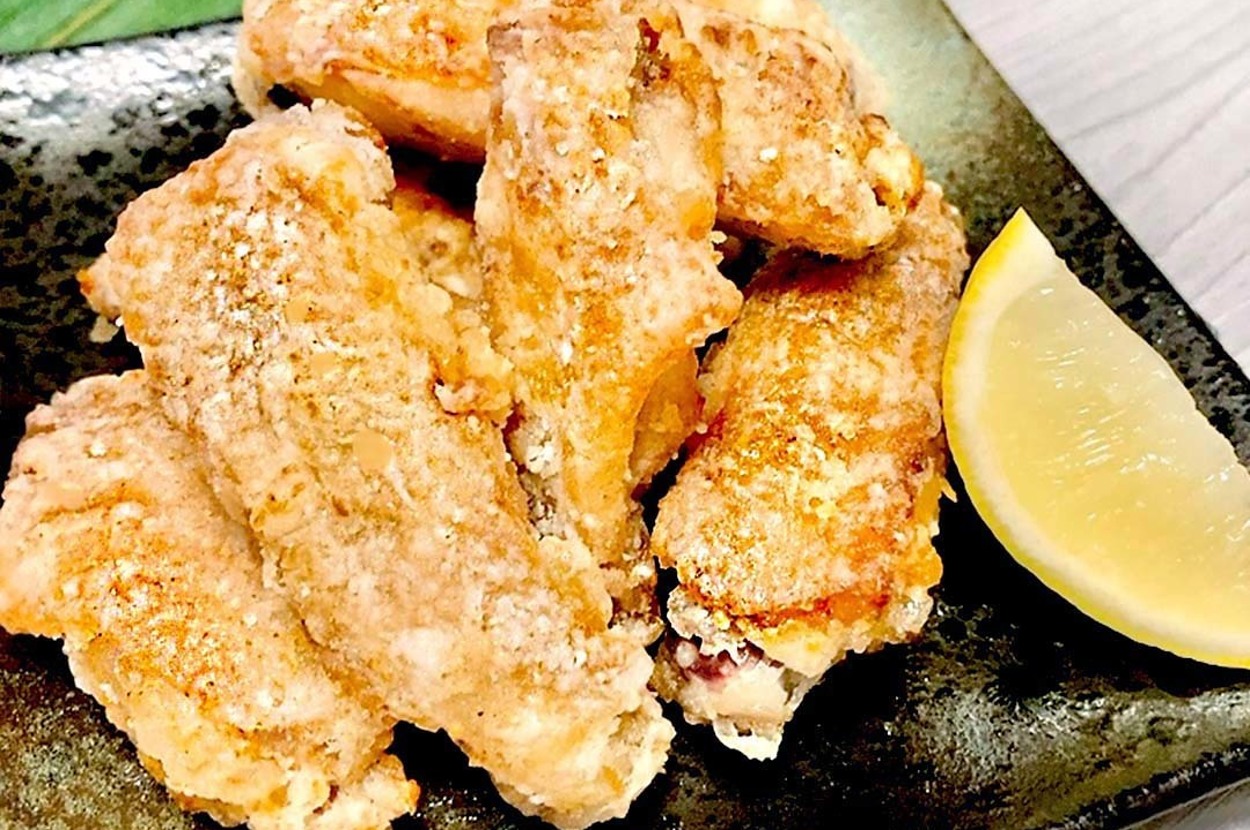 皿に盛られた揚げたカニの爪とレモンスライス。背景に葉。