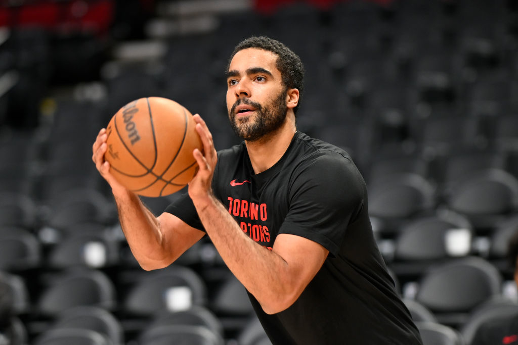 Jontay Porter in a Toronto Raptors shirt practicing basketball, focused on taking a shot, with empty stadium seats in the background