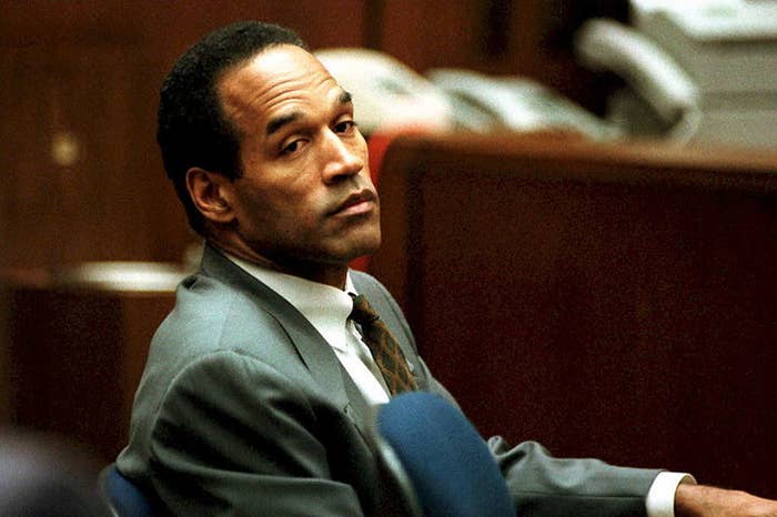 O. J. Simpson sits in a courtroom, wearing a suit and tie, looking towards the camera