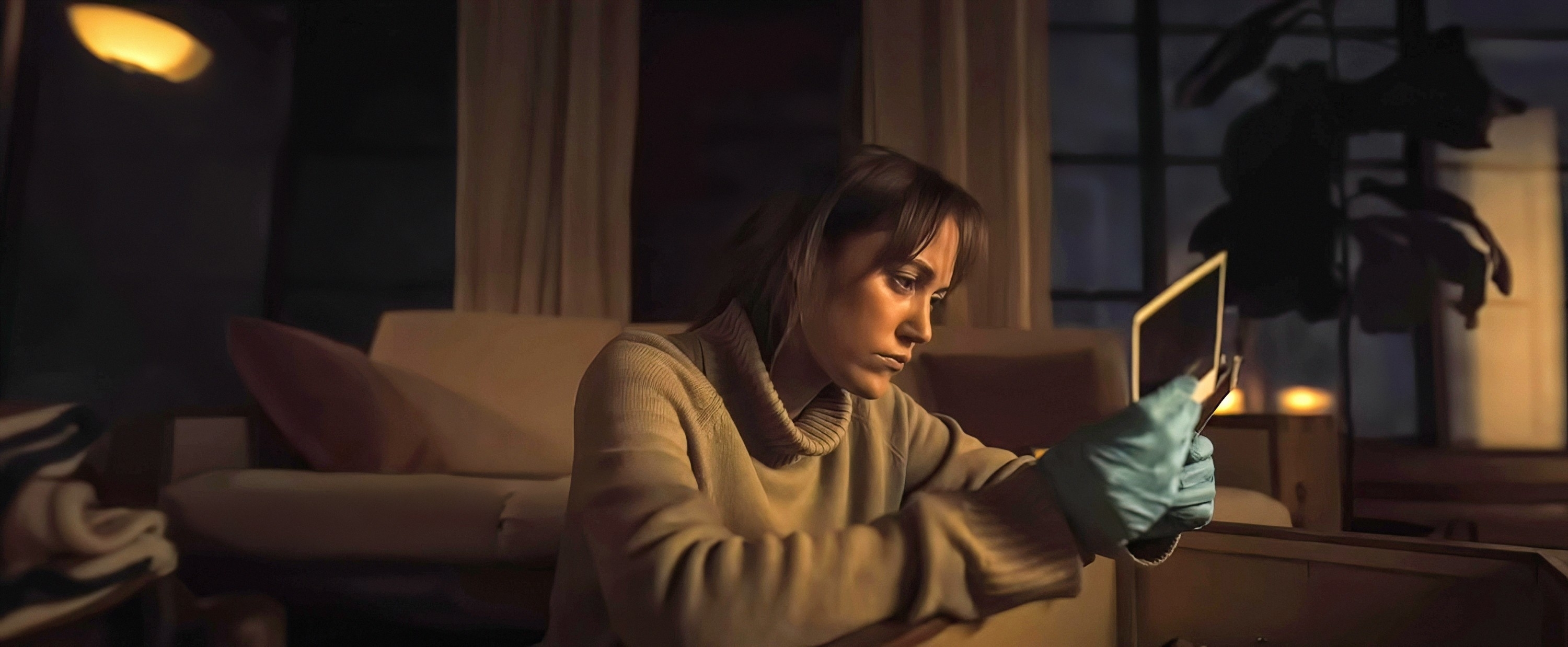 A woman, wearing a turtleneck and blue gloves, examines a photo inside a dimly lit room, suggesting an investigative or reflective moment