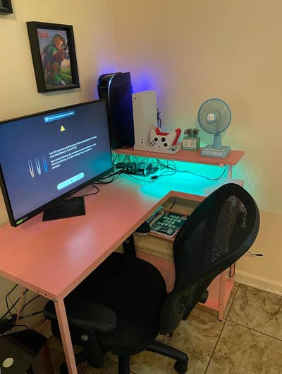 Home workspace setup featuring a computer, fan, and desk accessories, suitable for gaming or working