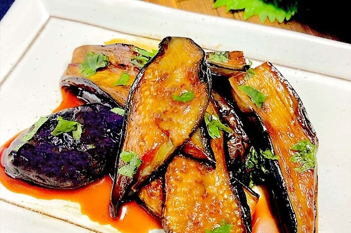 白い皿に盛られた、おろし大根や刻みねぎを添えたナスの照り焼き料理。