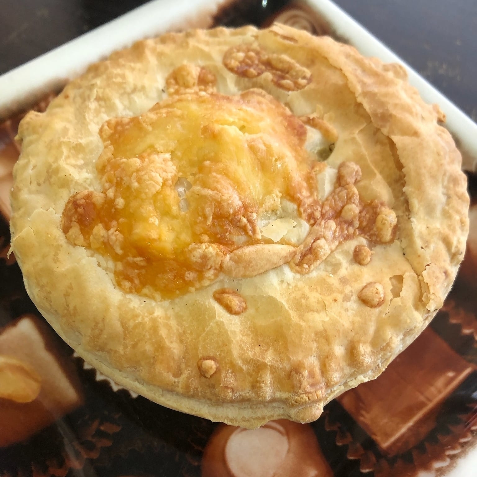 A flaky, round pie with cheese melted on top, sitting on a table
