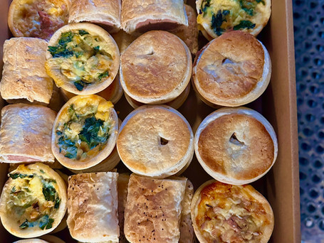 A variety of savory pastries including quiches and puff pastries arranged in a box
