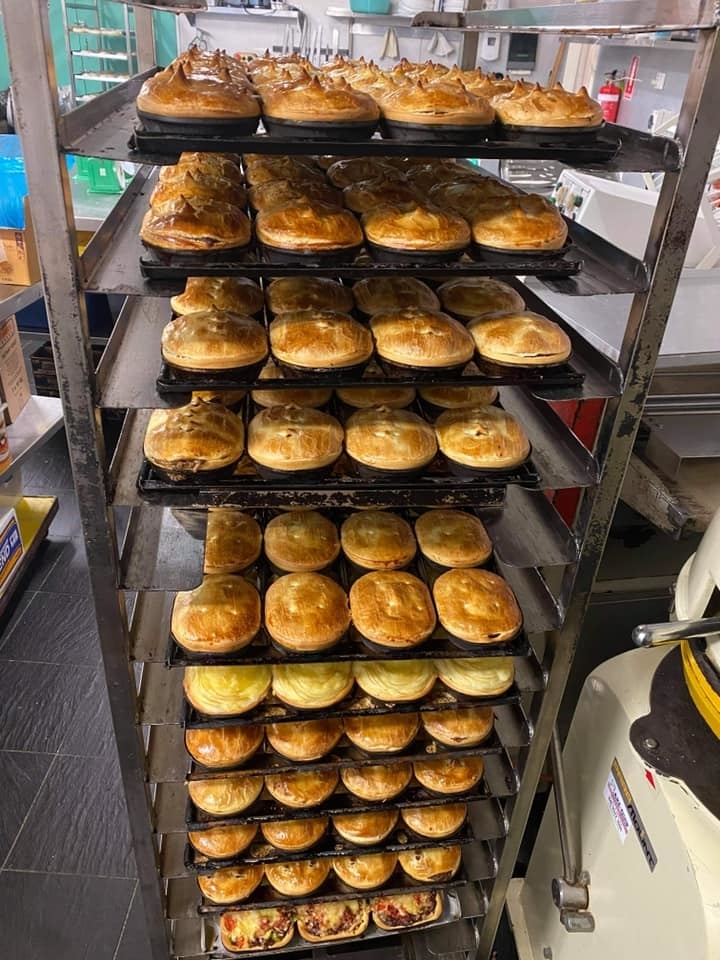 Freshly baked pies cooling on a multi-tiered rack in a commercial kitchen