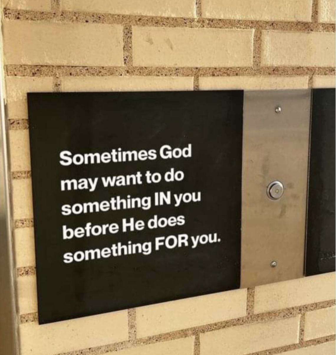 A sign on a brick wall reads: "Sometimes God may want to do something IN you before He does something FOR you."