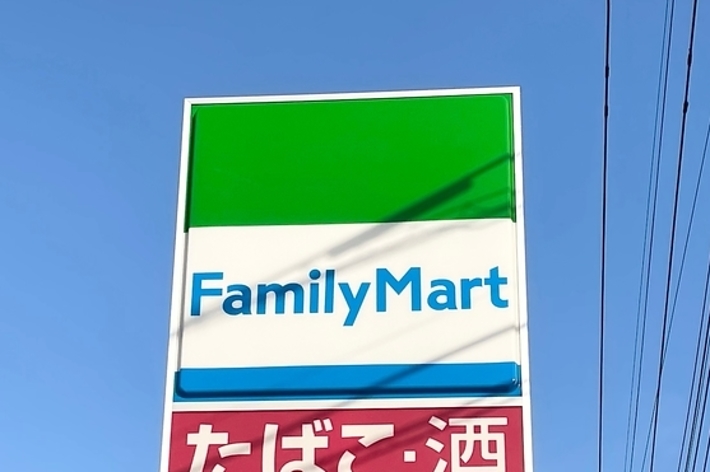 ファミリーマートの看板が青空を背景に掲示されている。たばこ、酒、銀行ATM、バリアフリー対応が利用可能。