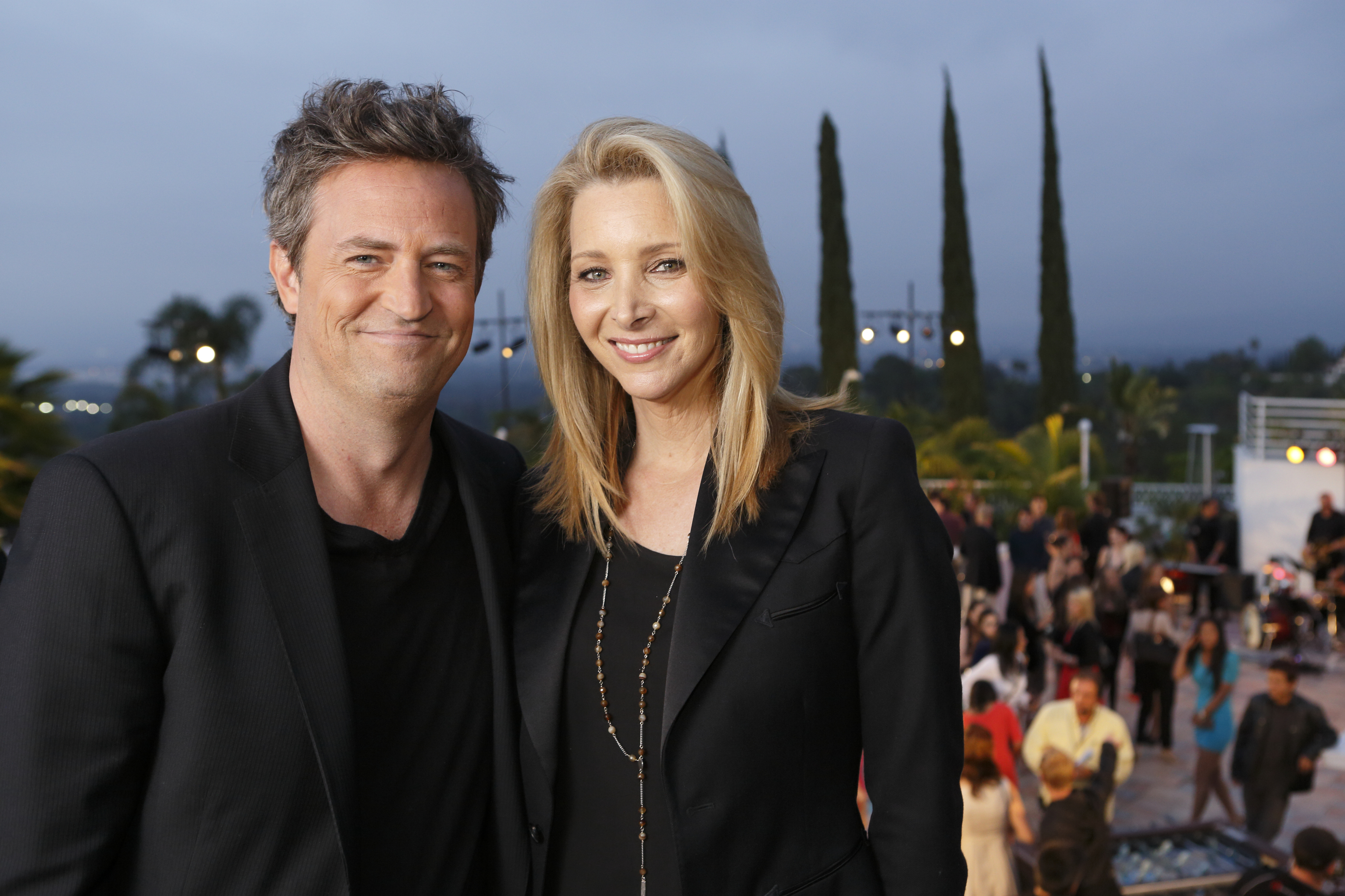 Matthew Perry and Lisa Kudrow smiling at an outdoor event, both wearing black outfits